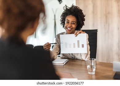 Portrait Of A Smiling African American Employee Showing Business Results To A Board Member.