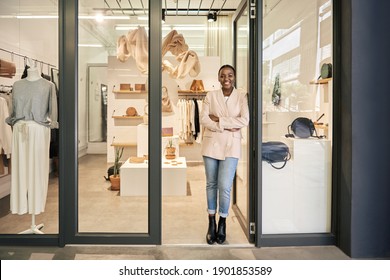 Porträt einer lächelnden afroamerikanischen Unternehmerin, die sich mit den Armen an ihre Ladentür gekreuzt hat