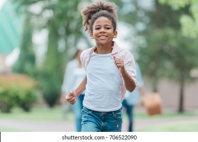 portrait of smiling african american little girl running in park - Powered by Shutterstock