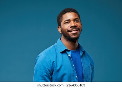 Portrait of smiling African American man wearing blue on blue background and looking at camera, copy space - Powered by Shutterstock