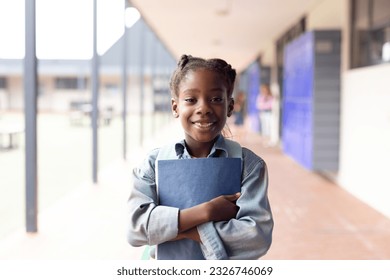 Portrait of smiling african american schoolgirl in elementary school corridor, with copy space. Education, inclusivity, elementary school and learning concept. - Powered by Shutterstock