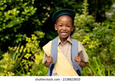 Portrait of smiling african american scout girl in uniform with backpack against plants. unaltered, girl scout, childhood, courage, leadership and scouting. - Powered by Shutterstock