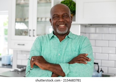 Portrait Of Smiling African American Senior Man With Arms Crossed Standing In Kitchen At Home. Unaltered, Lifestyle, Retirement, Domestic Life.