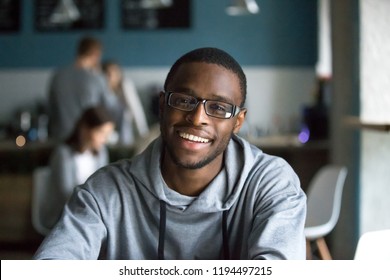 Portrait of smiling African American student looking at camera sitting in café, black millennial man posing making picture in coffeeshop, afro male in glasses drinking coffee working in coffeehouse - Shutterstock ID 1194497215