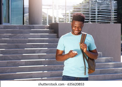 Portrait Of Smiling African American Student Looking At Cellphone