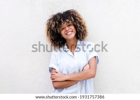 Portrait smiling african American teen girl with arms crossed by white background 