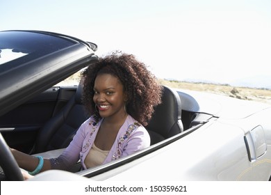 Portrait Of Smiling African American Woman Driving Convertible On Desert Road