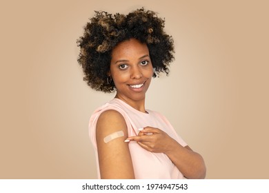 Portrait Of Smiling African American Woman Showing Her Arm With Band Aid After Coronavirus Covid-19 Vaccine Injection. Covid Vaccination Concept