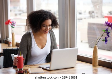 Portrait Of A Smiling African American Woman Using Laptop At Cafe