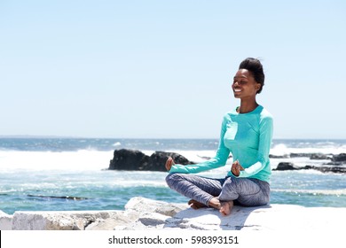 Portrait Of Smiling African American Woman Doing Yoga By The Sea
