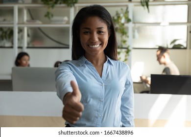 Portrait of smiling African American young female employee pose in modern office show thumbs up give recommendation, happy biracial millennial woman worker or client recommend good service