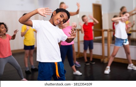 Porträt eines lächelnden afrikanischen Jungen, der während der Gruppenklasse im Tanzzentrum Tanzelemente zeigt