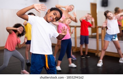Portrait Of Smiling African Boy Showing Dance Elements During Group Class In Dance Center