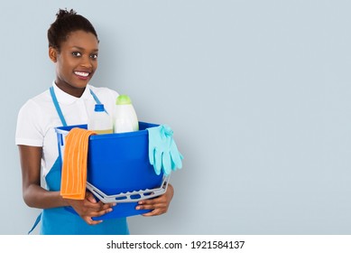 Portrait Of A Smiling African Female Janitor Holding Cleaning Equipment