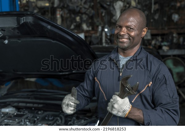 Portrait smiling\
african male mechanic holding wrench and tools working in car\
repair service, black man mechanic with mechanicl tools works in\
maintenance automobile garage\
shop
