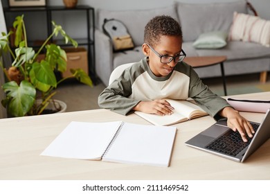 Portrait of smiling African-American boy wearing glasses using laptop while studying at home, homeschooling concept, copy space - Powered by Shutterstock