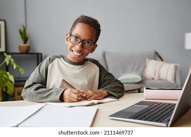 Portrait of smiling African-American boy wearing glasses while studying at home, homeschooling concept, copy space