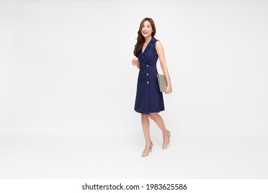 Portrait of a smiling Asian businesswoman holding laptop computer while walking isolated on white background, Full body length composition concept - Shutterstock ID 1983625586