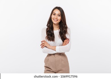 Portrait of a smiling asian businesswoman standing with arms folded and looking at camera isolated over white background