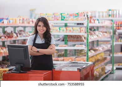 Portrait of smiling asian female cashier staff standing at cash counter in supermarket