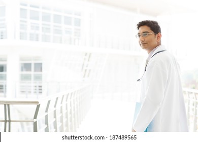 Portrait Of A Smiling Asian Indian Male Medical Doctor Walking Inside Hospital.