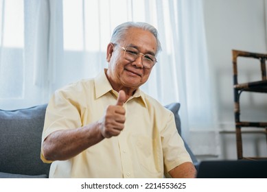 Portrait Of Smiling Asian Senior Mature Man Sitting On Couch Sofa Using Laptop Show Thumbs Up For Easy Technology, Happy Senior Old Male Recommend Good Quality Working On Computer At Home.