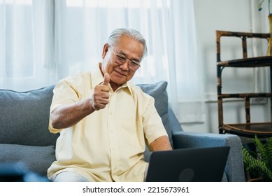 Portrait Of Smiling Asian Senior Mature Man Sitting On Couch Sofa Using Laptop Show Thumbs Up For Easy Technology, Happy Senior Old Male Recommend Good Quality Working On Computer At Home.