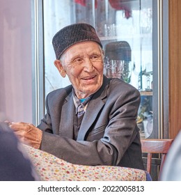 Portrait Of Smiling Asian Senior Muslim Man Sitting At Table At Home