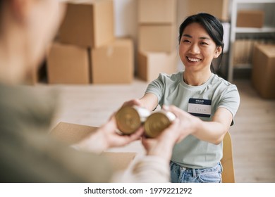 Portrait Of Smiling Asian Woman Volunteering At Help And Donations Event, Packing Canned Food In Boxes, Copy Space