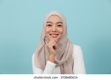 Portrait Of Smiling Asian Young Muslim Woman In Hijab Head Scarf Standing Against Blue Colour Background