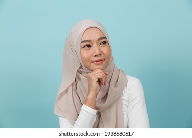 Portrait Of Smiling Asian Young Muslim Woman In Hijab Head Scarf Standing Against Blue Colour Background