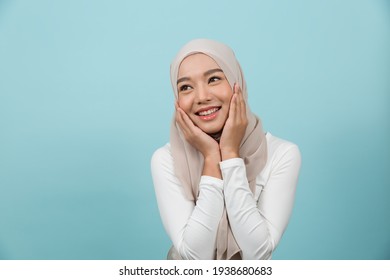 Portrait Of Smiling Asian Young Muslim Woman In Hijab Head Scarf Standing Against Blue Colour Background