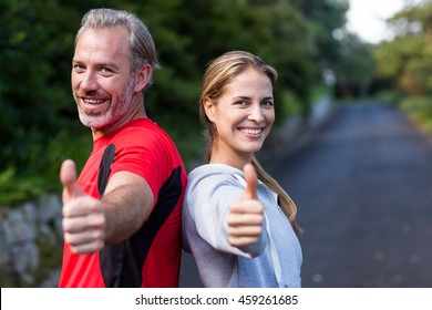 Portrait of smiling athletic couple showing thumbs up - Powered by Shutterstock