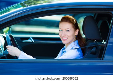 Portrait Smiling, Attractive Brunette Woman, Buckled Up, Driving, Testing Her New Black Car, Automobile, Purchased At Dealership, Isolated Street, City Traffic Background. Safe Driving Habits Concept