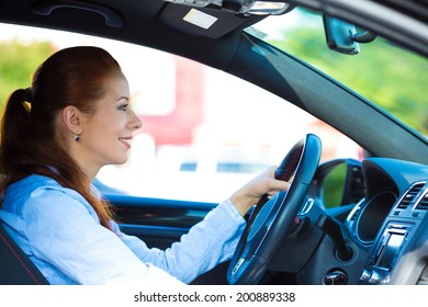 Portrait Smiling, Attractive Brunette Woman, Buckled Up, Driving, Testing Her New Black Car, Automobile, Purchased At Dealership, Isolated Street, City Traffic Background. Safe Driving Habits Concept