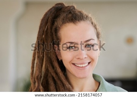 Portrait of smiling attractive girl with dreads in ponytail posing in modern office