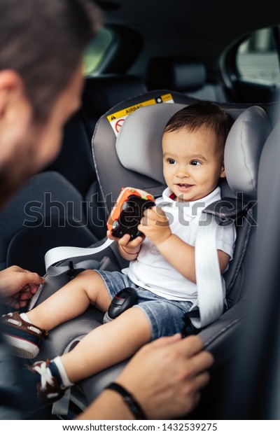 portrait of\
smiling baby and father in car child\
seat