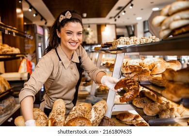 Portrait of smiling bakery worker holding freshly baked pastries in bakery shop. - Powered by Shutterstock