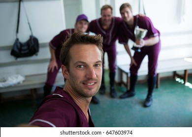 Portrait of smiling baseball team clicking selfie while standing at locker room after match - Powered by Shutterstock