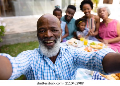 Portrait of smiling bearded bald senior african american man taking selfie with family at brunch. family, love and togetherness concept, unaltered.