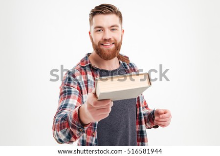 Portrait of a smiling bearded guy in plaid shirt giving book to camera over white background