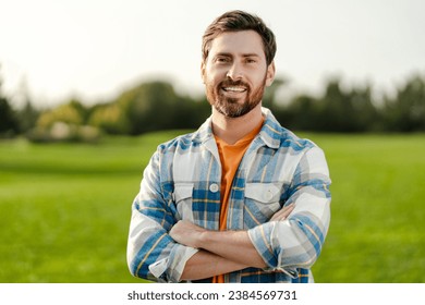 Portrait of smiling bearded man farmer with crossed arms standing in field, outdoors, looking at camera. Advertisement concept - Powered by Shutterstock