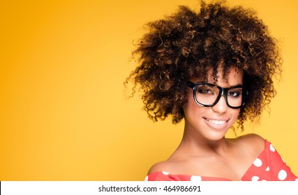 Portrait of smiling beautiful african american young woman. Girl with afro wearing eyeglasses. Yellow background. Studio shot.  - Shutterstock ID 464986691