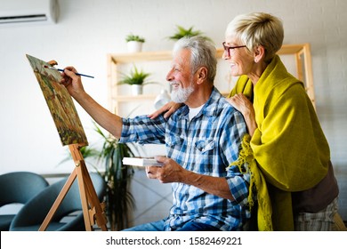 Portrait of smiling beautiful elderly couple painting - Powered by Shutterstock