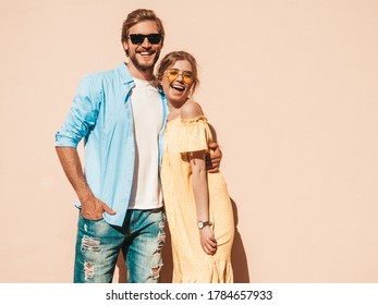 Portrait Of Smiling Beautiful Girl And Her Handsome Boyfriend. Woman In Casual Summer Dress And Man In Jeans. Happy Cheerful Family. Female Having Fun In The Street Near Wall