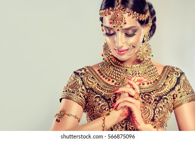 Portrait  smiling of beautiful indian girl. Young hindu woman model with golden kundan jewelry set . Traditional Indian costume lehenga choli .