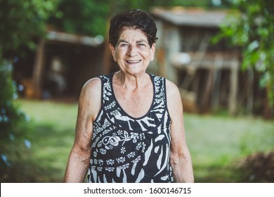 Portrait Of Smiling Beautiful Older Female Farmer. Woman At Farm In Summer Day. Gardening Activity. Brazilian Elderly Woman.