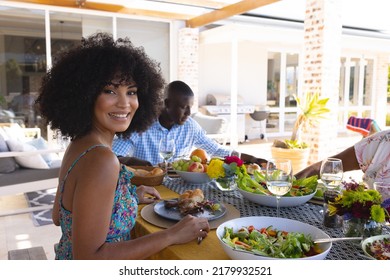 Portrait of smiling beautiful woman with afro hair having lunch with family at dining table at home. Food, drink, happy, unaltered, togetherness, love, lifestyle and retirement concept. - Powered by Shutterstock