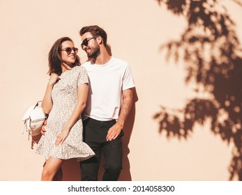 Portrait of smiling beautiful woman and her handsome boyfriend. Woman in casual summer clothes. Happy cheerful family. Female having fun. Couple posing in the street near wall in sunglasses