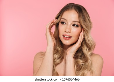 Portrait of a smiling beautiful young girl with blonde curly hair standing isolated over pink background, posing, touching face - Shutterstock ID 1396564466